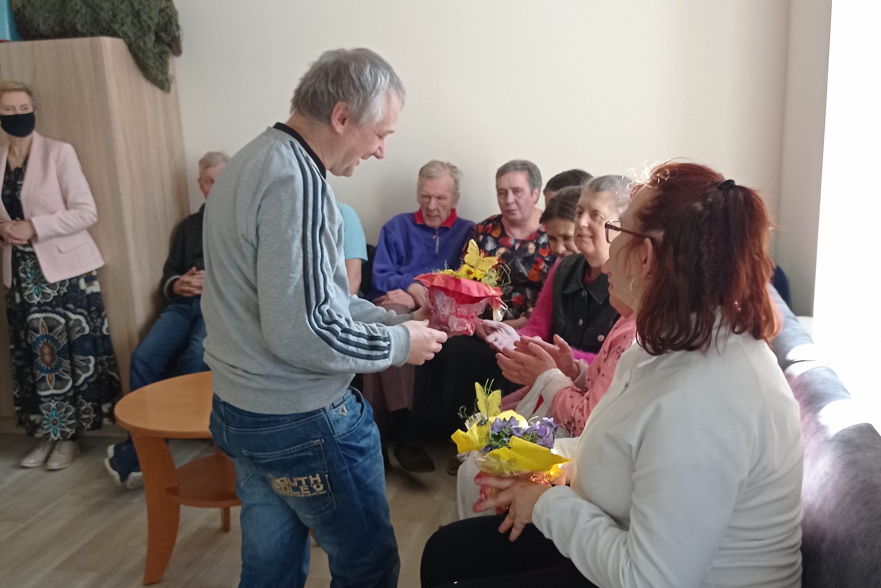 mężczyzna rozdaje kwiaty siedzącym kobietom